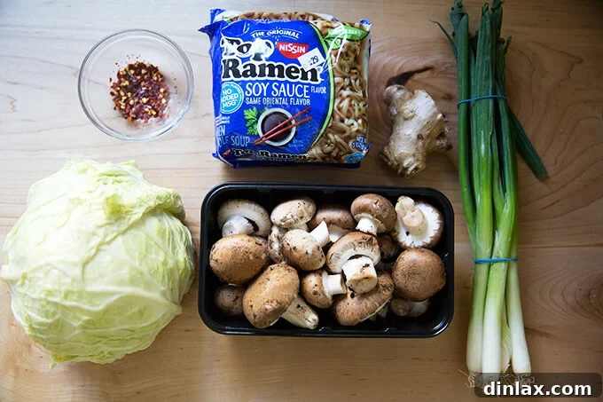 An overhead shot of the ingredients to make one-pot ginger-scallion ramen noodles, including fresh cabbage, mushrooms, ginger, and pantry staples.