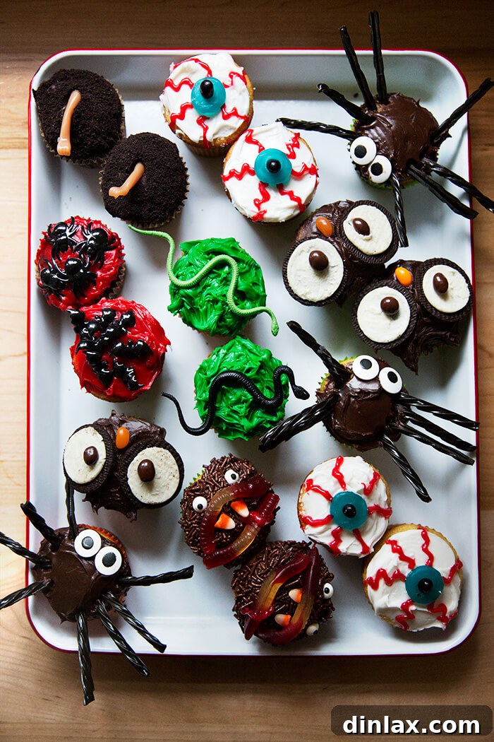 A tray filled with festively decorated Halloween cupcakes, including owls, ghosts, and spiders.