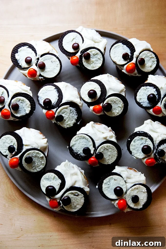 A plate of adorable snowy owl Halloween cupcakes with white frosting, Oreo eyes, and orange candy beaks.