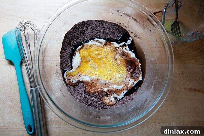 A bowl containing both wet and dry ingredients for one-bowl chocolate cupcakes, ready to be mixed.