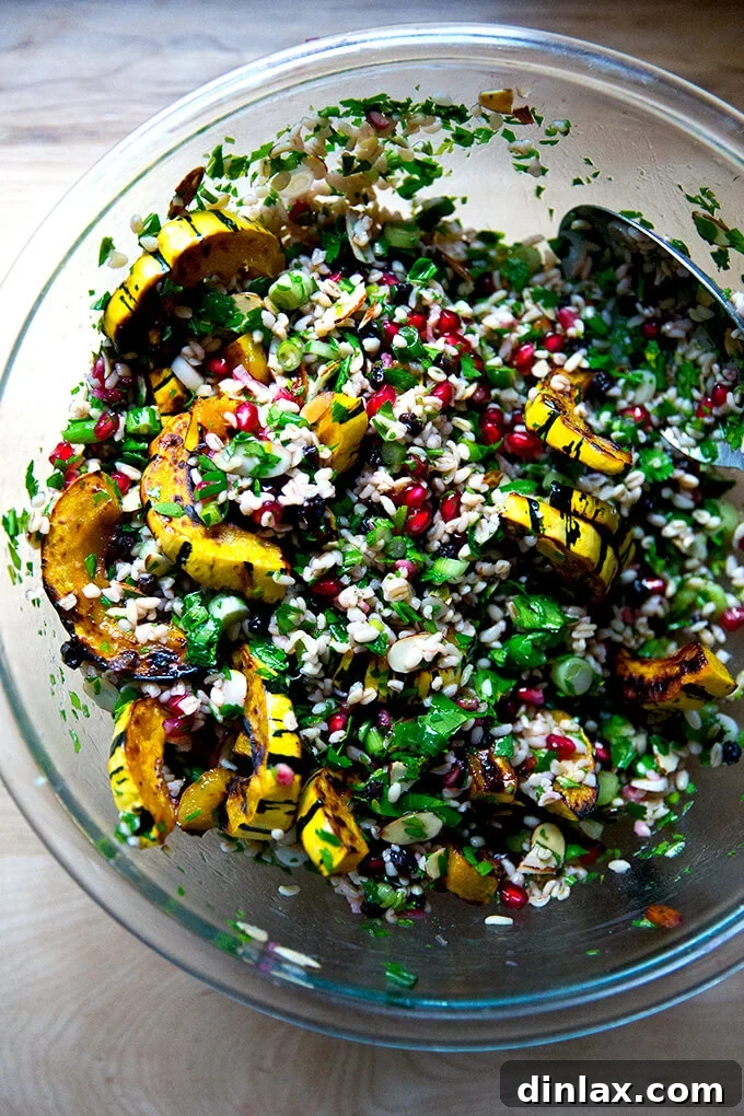 An overhead shot of a large glass bowl filled with winter tabbouleh and roasted delicata squash, gently tossed together to combine all ingredients.