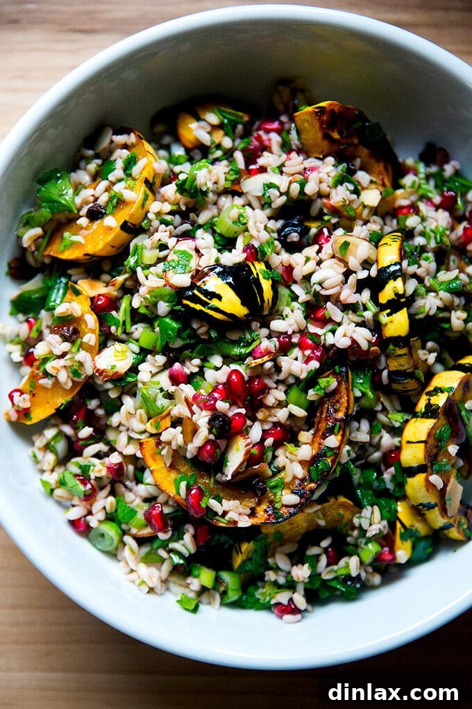 A beautifully presented white serving bowl brimming with winter tabbouleh and perfectly roasted delicata squash slices, garnished with fresh herbs.