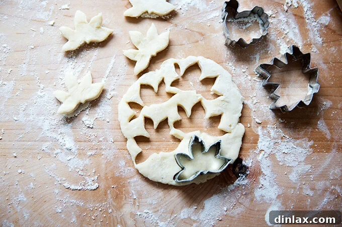 Leftover pie dough rolled out and cut out with various cookie cutters, including leaf and turkey shapes, ready for baking.