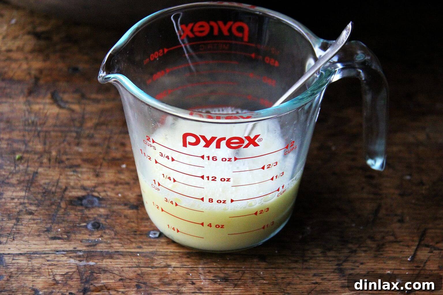 A liquid measuring cup holding a whisked mixture of egg and stock, ready to be incorporated into the stuffing.