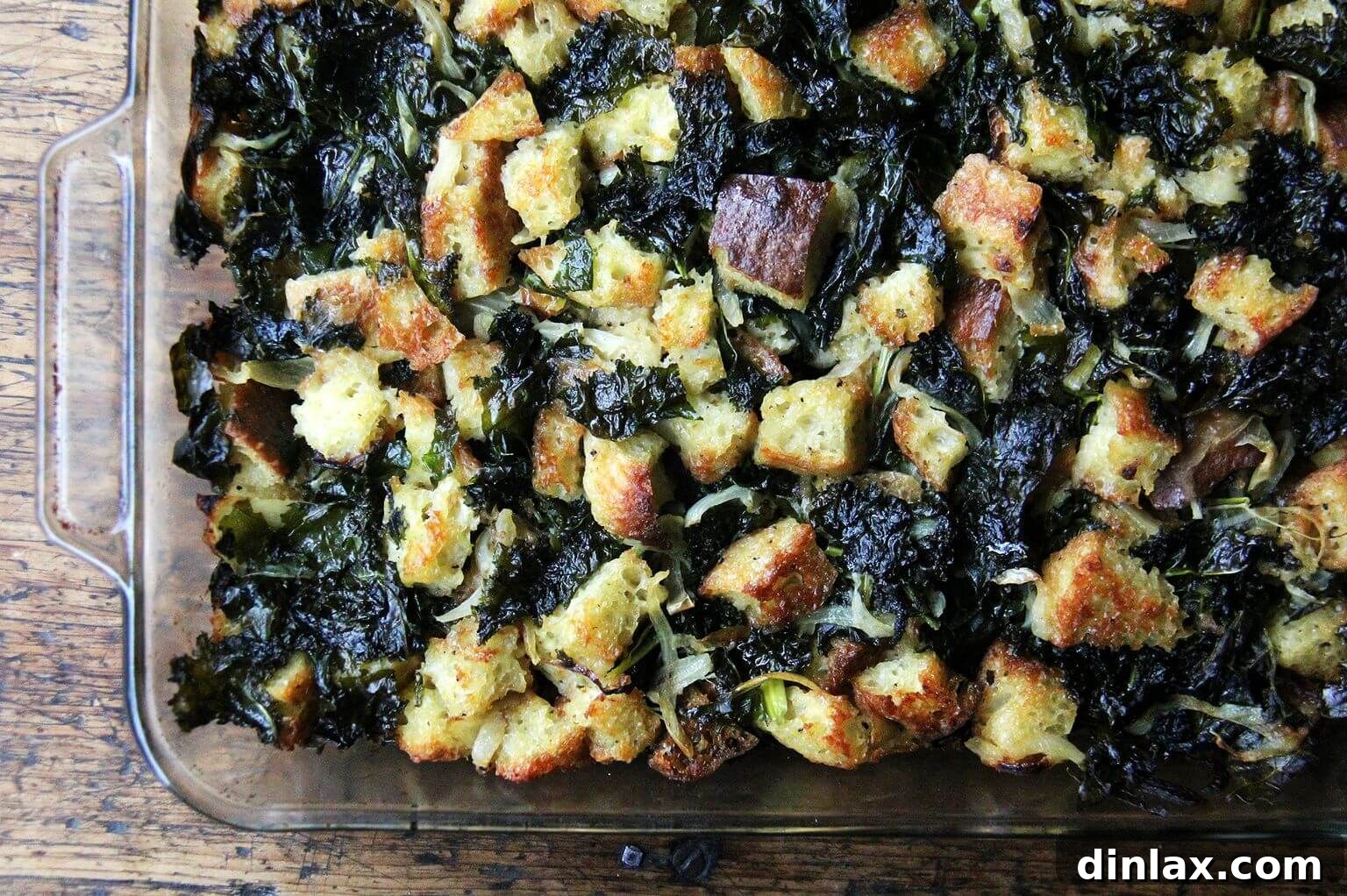 An overhead shot of a 9x13-inch pan brimming with beautifully baked kale and caramelized onion stuffing, boasting a golden crust.