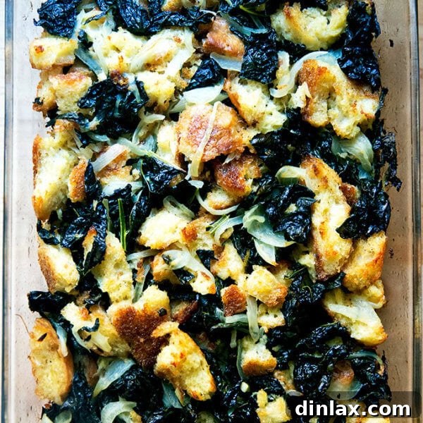 A close-up shot of a golden-brown kale and caramelized onion stuffing, baked to perfection in a square dish.
