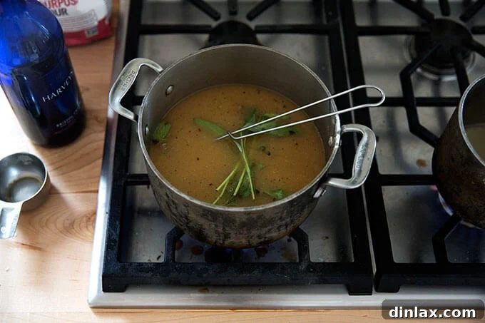 A saucepan filled with gravy simmering with sage.
