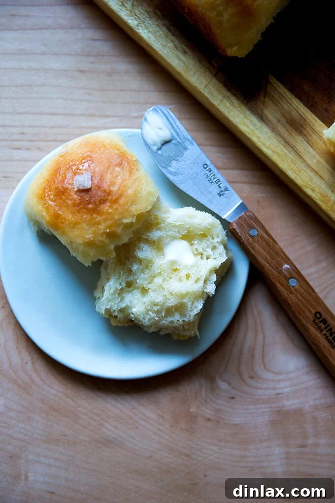 A single buttermilk pull-apart roll on a plate, delicately spread with butter, showcasing its tender texture.