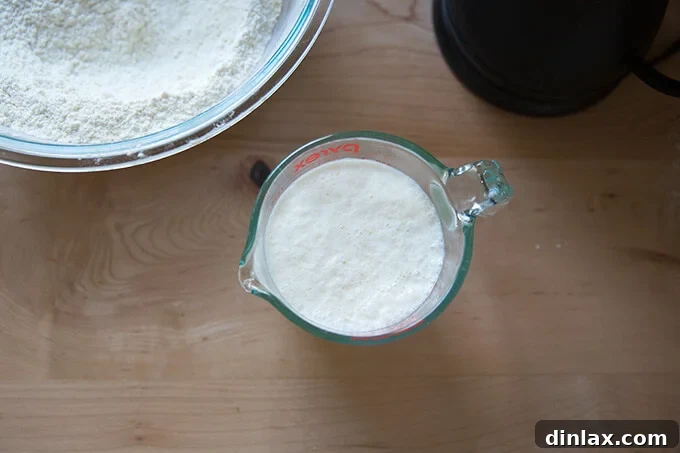 An overhead shot of a glass measuring cup holding buttermilk and hot water, allowing the mixture to warm slightly.