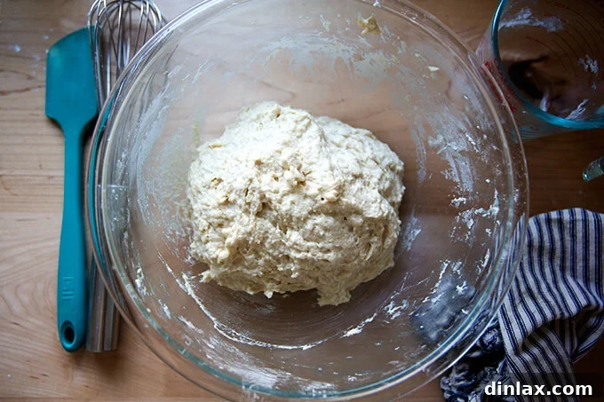 Just-mixed buttermilk pull-apart bread dough in a large glass bowl, showcasing its sticky consistency.