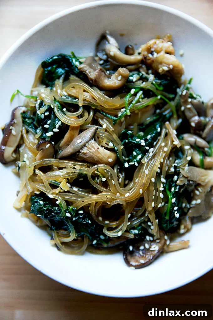 Japchae: Vegetarian Korean Glass Noodles 17 A beautifully presented bowl of japchae, featuring glossy noodles, colorful vegetables, and a sprinkle of sesame seeds, ready to be enjoyed.