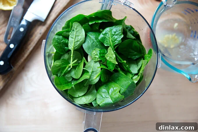 Sun-Kissed Tomato and Spinach Pesto Crostini 4 Overhead view of a food processor bowl, brimming with fresh spinach, about to be combined with other pesto ingredients.