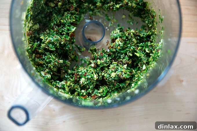 Sun-Kissed Tomato and Spinach Pesto Crostini 5 Close-up of a food processor bowl after pulsing, showing the finely chopped yet textured sun-dried tomato and spinach pesto mixture.