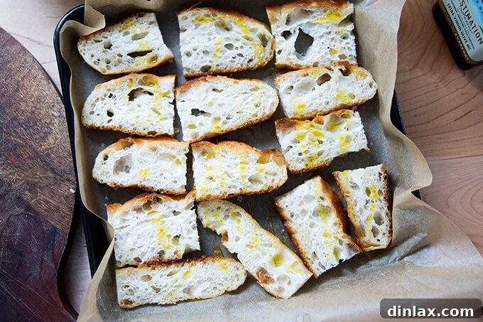 Sun-Kissed Tomato and Spinach Pesto Crostini 8 Thinly sliced focaccia bread arranged on a sheet pan, lightly drizzled with olive oil, ready for baking.