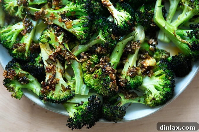 Spicy sesame-scallion sizzle being poured generously over a platter of freshly broiled broccoli, enhancing its flavor and visual appeal.