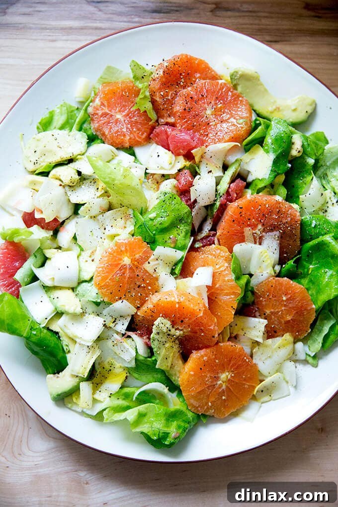 A platter topped with an endive, grapefruit and avocado salad, garnished with shaved parmesan.