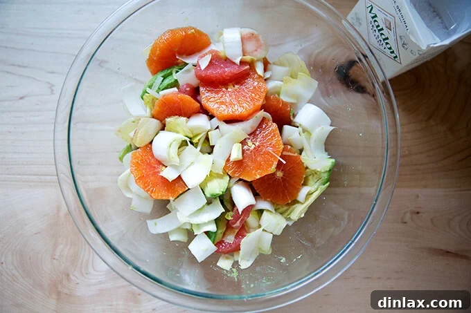 Citrus, avocado, and endive in a bowl, seasoned with flaky sea salt.