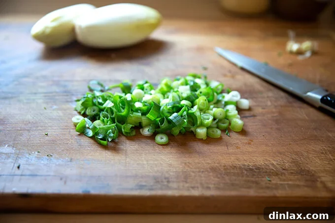 Neatly chopped scallions on a cutting board, adding a fresh, green element.