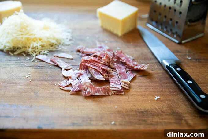 Finely chopped salami on a cutting board, ready to be added to the salad.