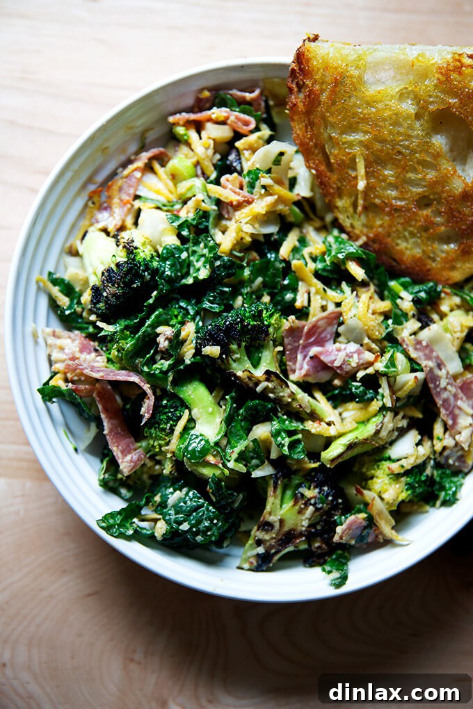 A bowl of Charred Broccoli Chopped Salad with spicy cashew dressing, served alongside a slice of toasted crusty bread.