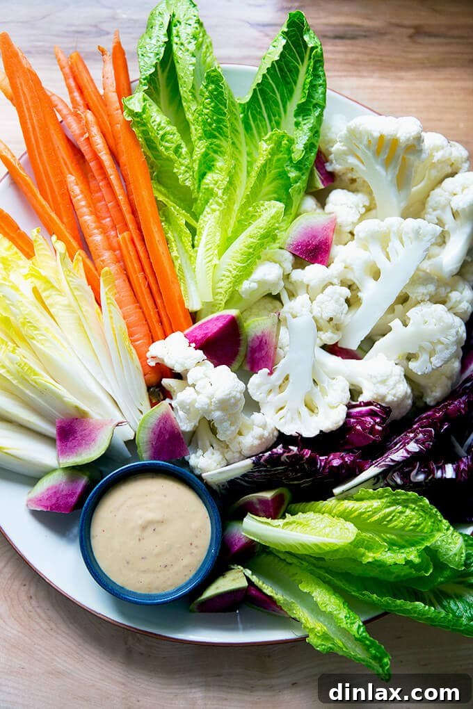 A colorful platter of fresh crudités, including carrots and cauliflower, served with a creamy spicy cashew dip.