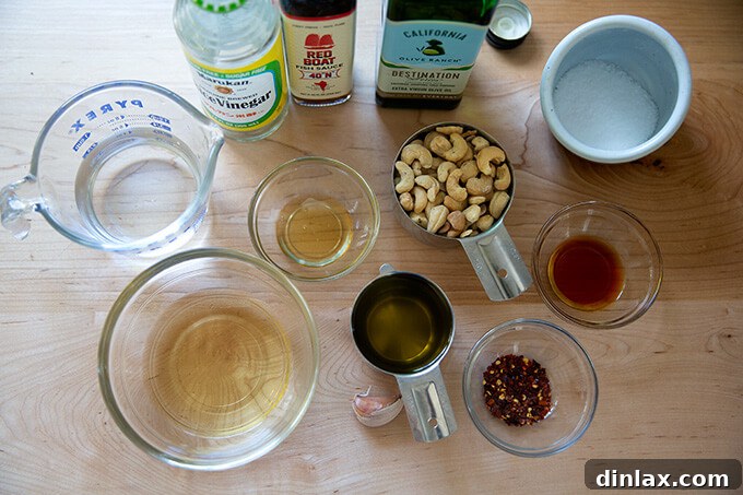 Ingredients for spicy cashew dressing, including cashews, garlic, honey, rice vinegar, fish sauce, red pepper flakes, and olive oil.