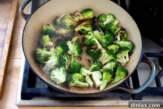 A sauté pan filled with perfectly charred broccoli florets, showing crispy edges and tender centers.