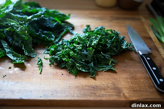 Finely chopped kale on a wooden cutting board, ready for the salad mix.