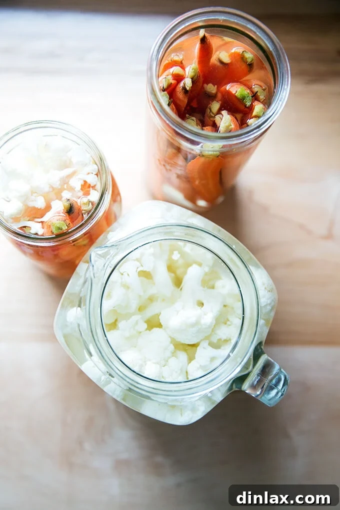 Overhead shot of freshly pickled carrots and cauliflower in glass jars, ready for the fridge.