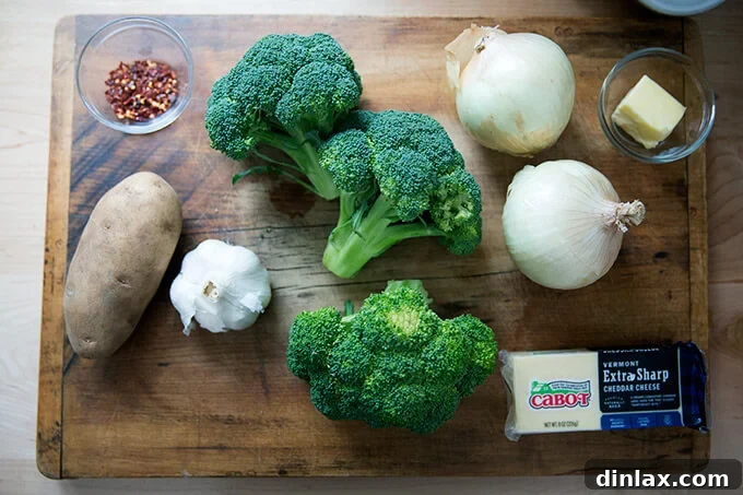 Golden Cheddar Broccoli Bisque 3 A selection of fresh ingredients laid out on a wooden board, including broccoli, potatoes, onions, and garlic, ready for making broccoli-cheddar soup.