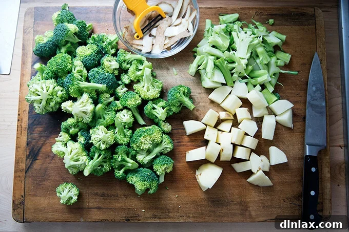 Golden Cheddar Broccoli Bisque 6 A medley of broccoli florets, cubed potatoes, and chopped broccoli stems are neatly arranged on a board, prepped for the soup recipe.