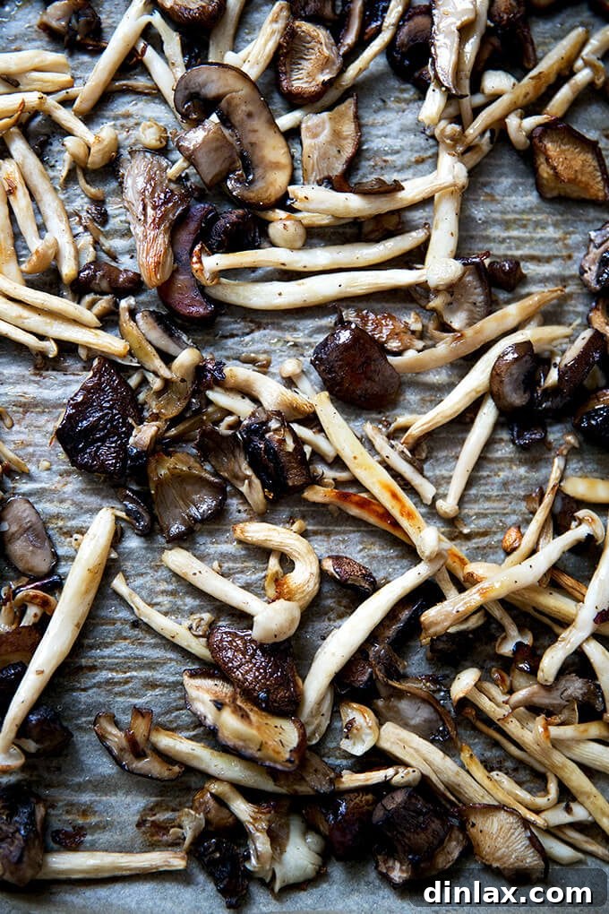 A sheet pan filled with perfectly roasted mushrooms, golden brown and tender, having just come out of the oven.
