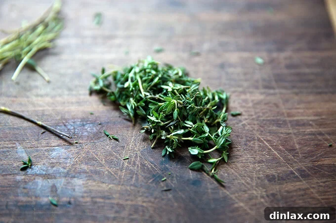 Fresh thyme leaves neatly chopped and scattered on a wooden cutting board, ready for use.