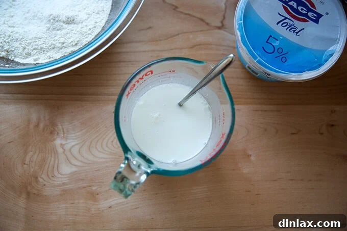 A liquid measuring cup filled with a mixture of hot water and Greek yogurt.