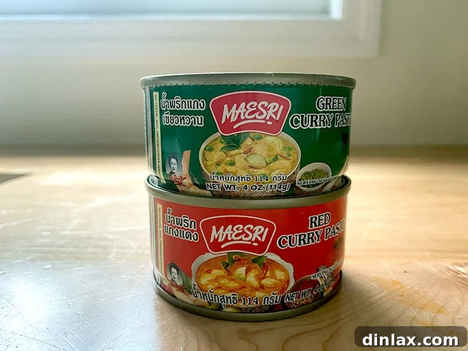 Two containers of Maesri red and green Thai curry pastes, essential for authentic flavor.