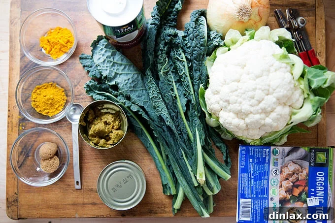 A selection of fresh ingredients including cauliflower, kale, tofu, and various spices for a quick vegetarian curry.