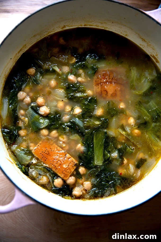A large pot of chickpea and escarole soup, having just finished simmering, steaming with aromatic goodness.