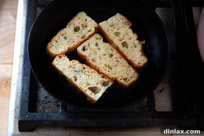Slices of focaccia bread sizzling in a skillet, turning golden brown as they toast in olive oil.