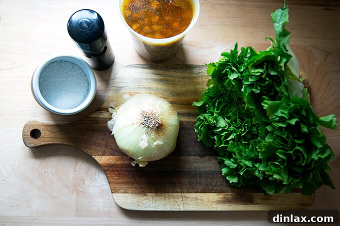 A simple array of fresh ingredients for chickpea and escarole soup, neatly arranged on a wooden board.