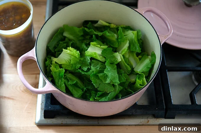 Chopped escarole added to the sautéed onions in a Dutch oven, ready to wilt.