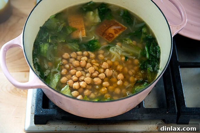 All the main ingredients — chickpeas, broth, and escarole — combined in a Dutch oven, poised for simmering.