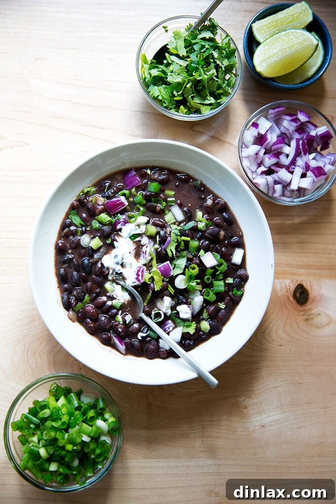 A comforting bowl of Cal Peternell's black bean soup, garnished with fresh onion, scallions, sour cream, and lime.