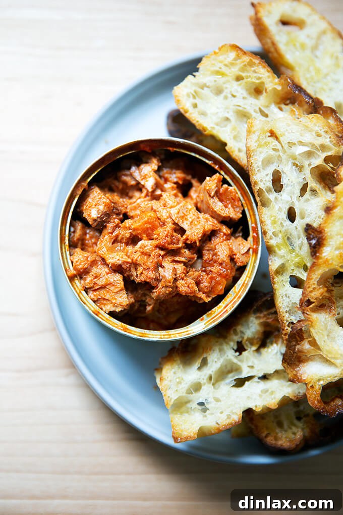 Korean Fire Tuna Crostini 10 A stunning spread featuring Korean double hot tuna in its original tin, surrounded by golden, crispy focaccia crostini, creating a perfect appetizer pairing.