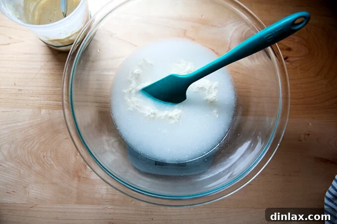 Unlock the Best Sourdough Pizza Crust 5 A bowl on a scale with a spatula and water, sourdough starter, and salt.