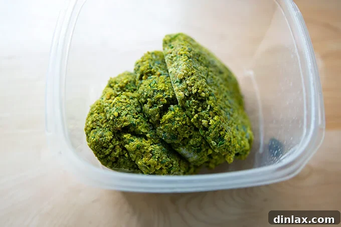 Stack of frozen falafel burgers neatly packed in an airtight container for efficient freezer storage.