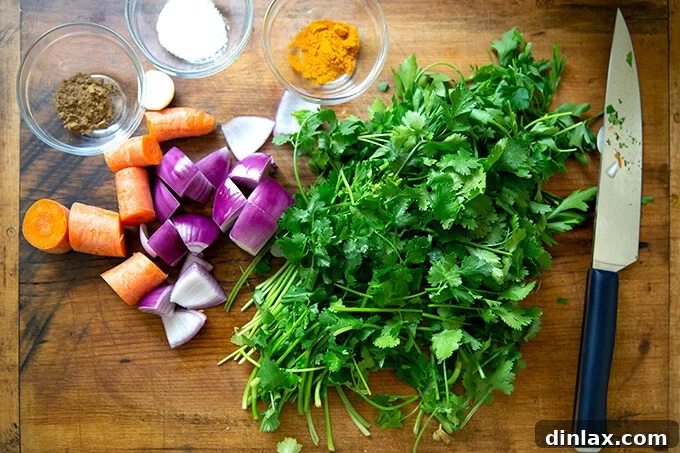 A collection of fresh ingredients for falafel burgers, including herbs, vegetables, and spices, neatly arranged on a cutting board.