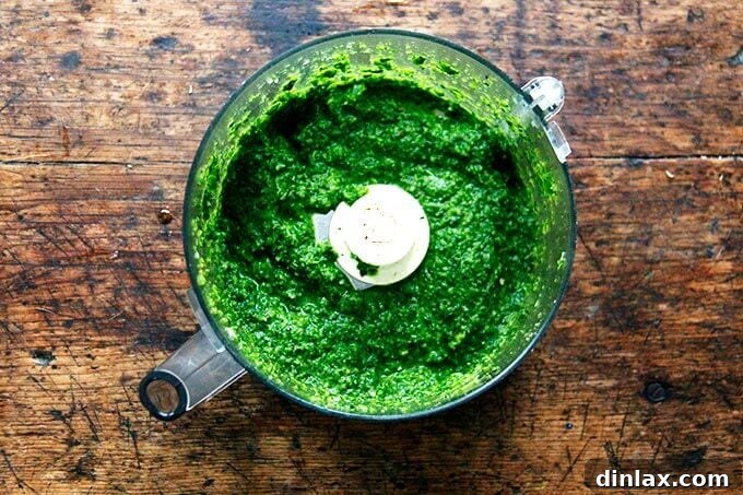 A food processor bowl with the finished Schug, a vibrant green sauce.