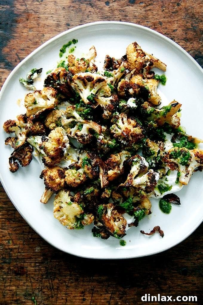 A plate of perfectly roasted cauliflower florets topped with a dollop of green Schug.