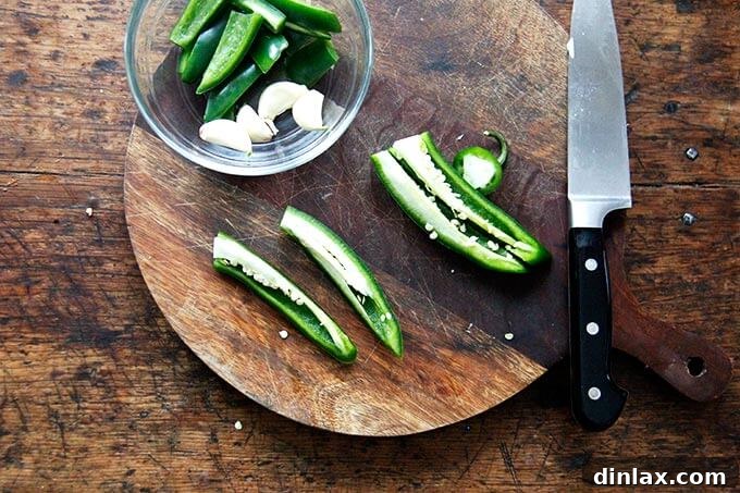 A hot green chili pepper on a cutting board, prepared for seeding.