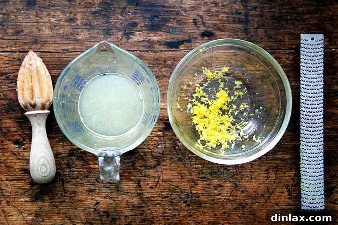 A liquid measure filled with fresh lemon juice next to a bowl of lemon zest.
